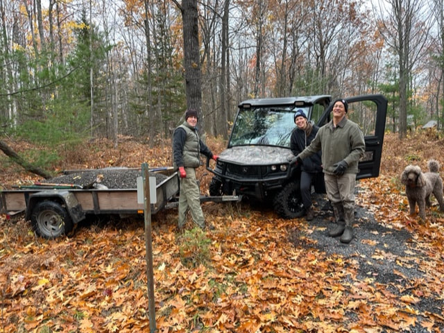 3 volunteers standing by a UTV with a trailer full of gravel