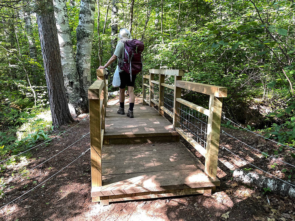 Person walking across one of the wooden bridges on the trail