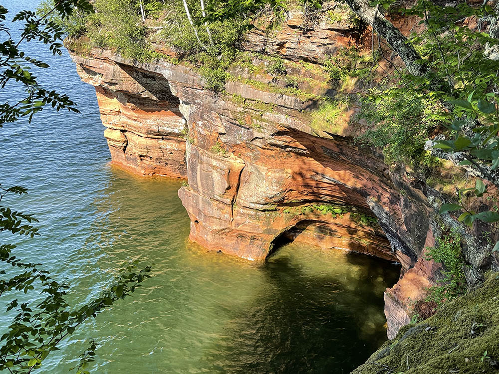 View across water with caves carved into Sandstone.